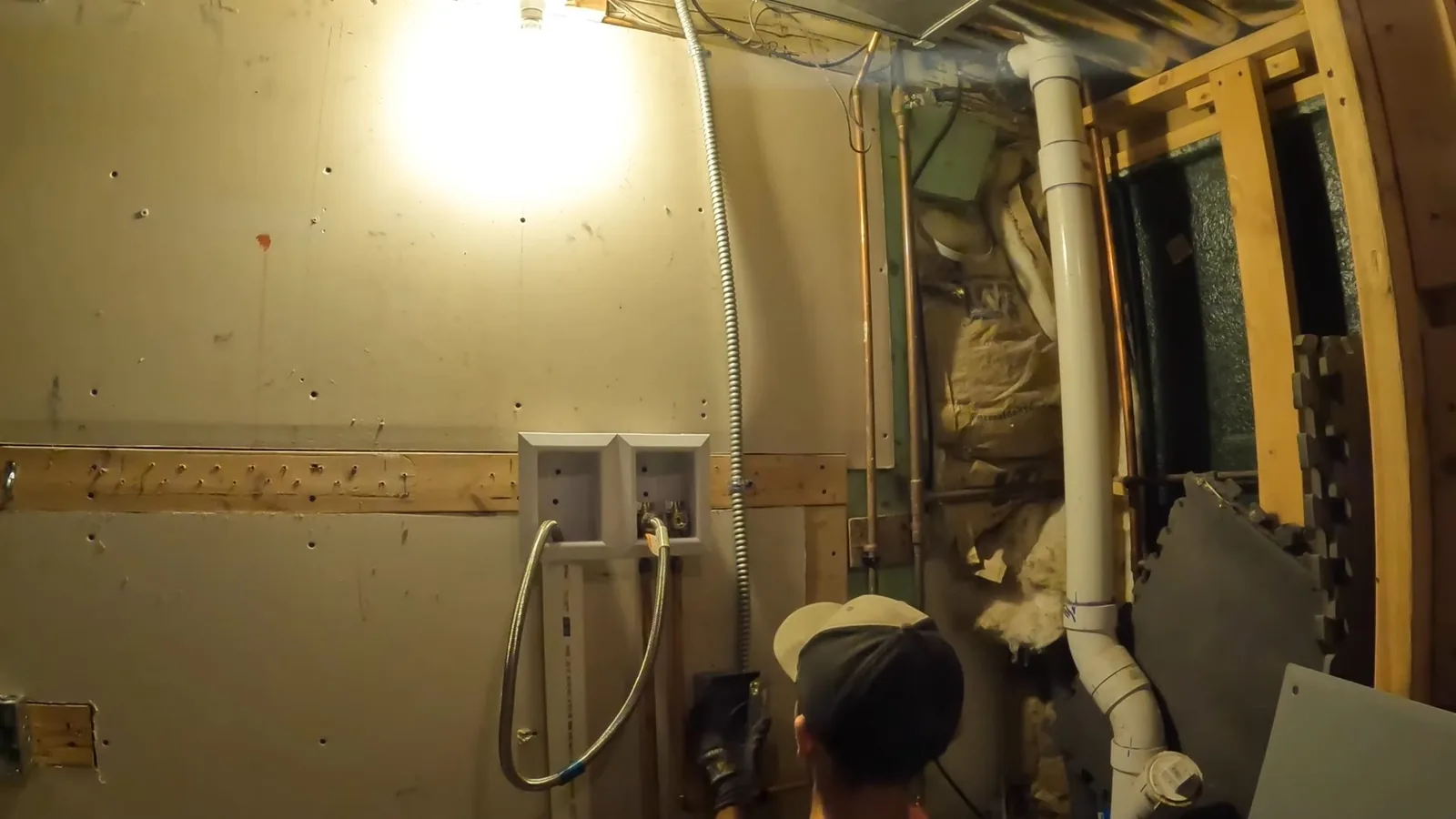 Framed utility wall with outlet boxes, a white drain pipe and insulation, and a cap at the bottom edge