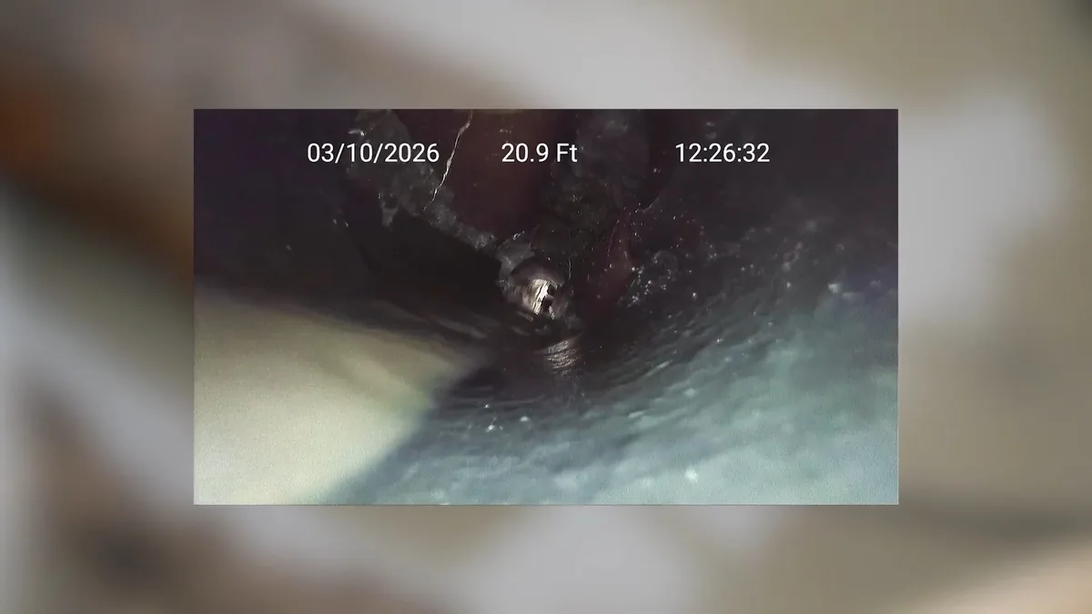 Round view down the inside of a drain pipe from a camera, with a date, depth and time overlay