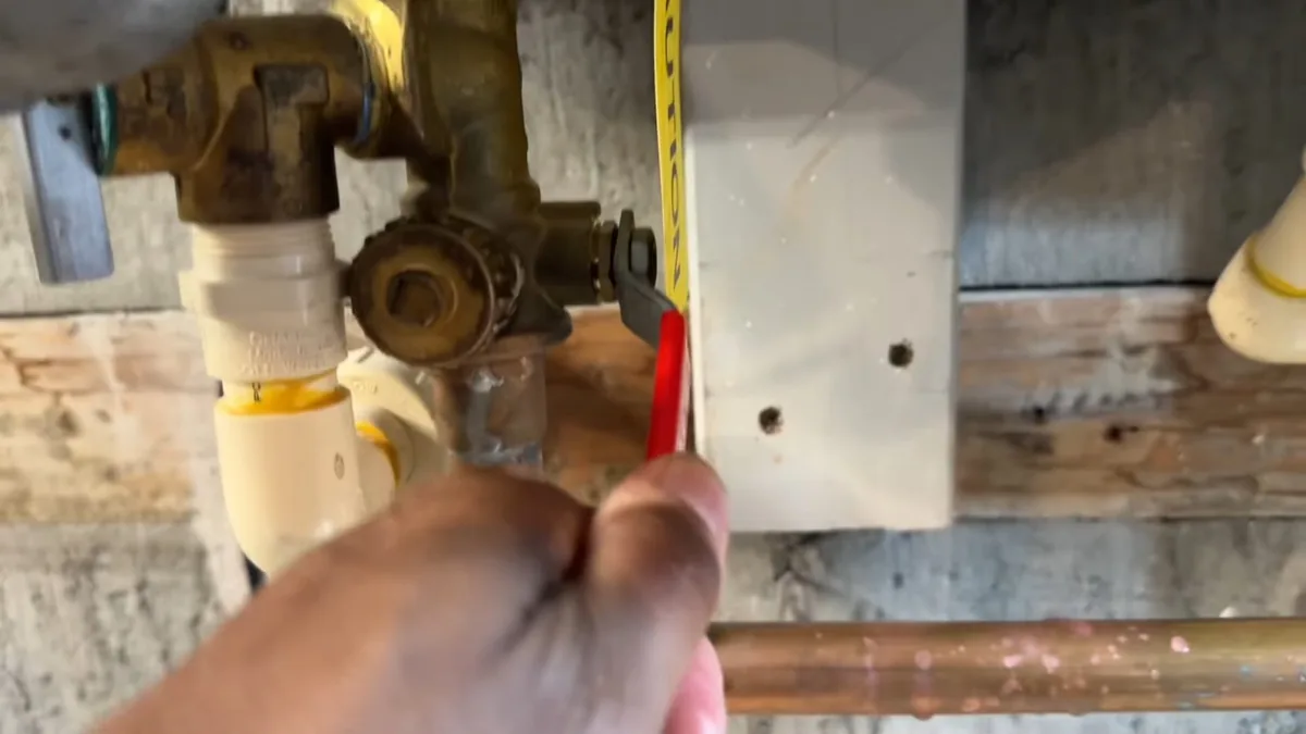 Hand holding a tape measure near brass valves and yellow gas fittings at a tankless heater