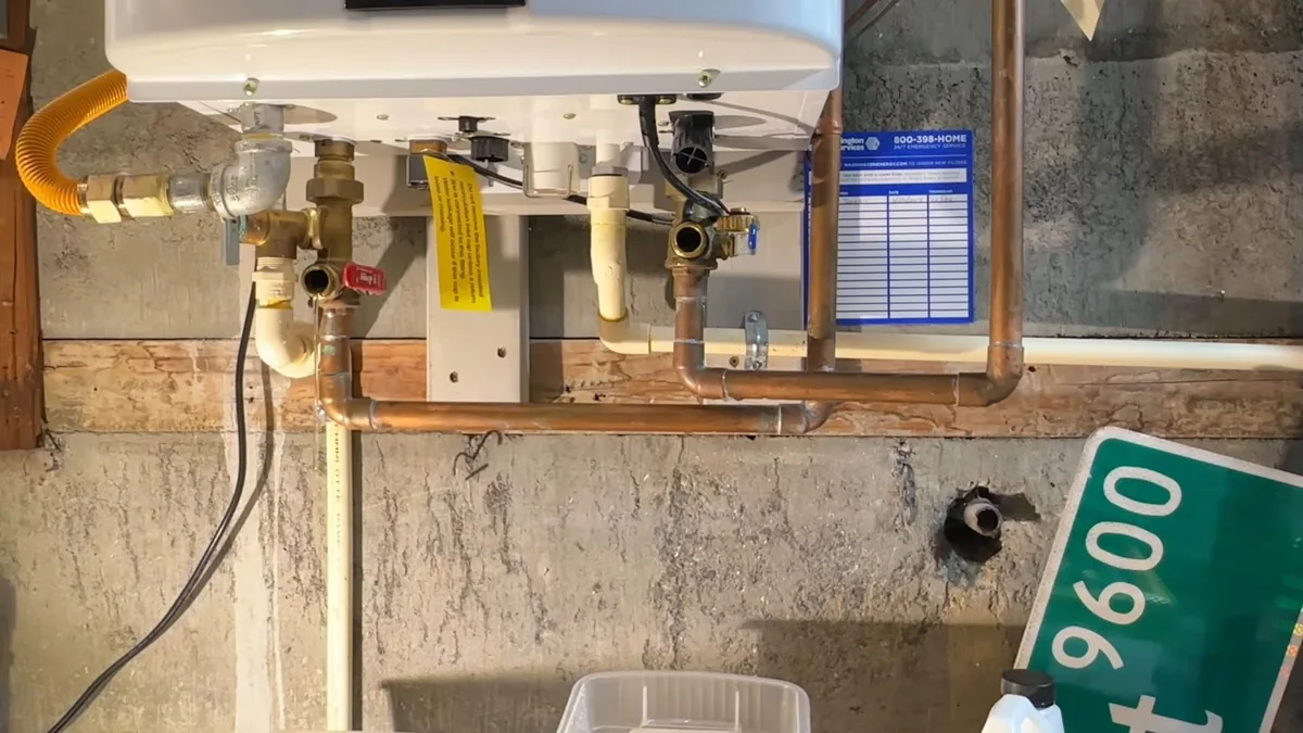 Yellow gas line, copper pipes and shutoff valves below a wall-mounted tankless heater