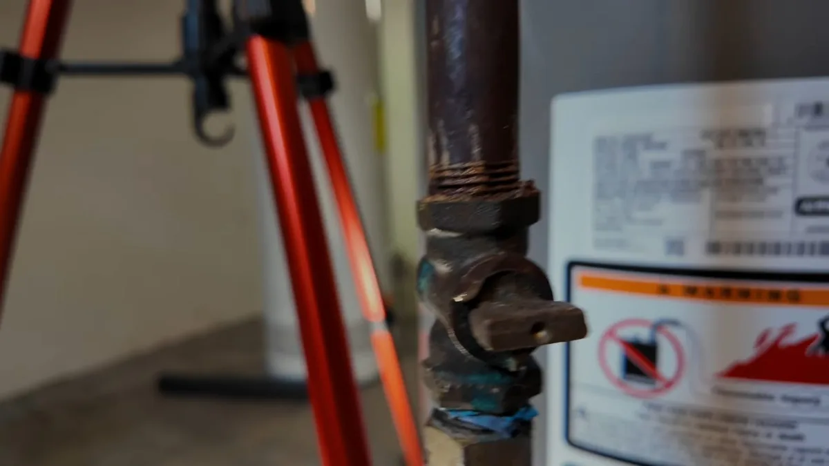 Warning label on the side of a tank water heater beside a gas valve