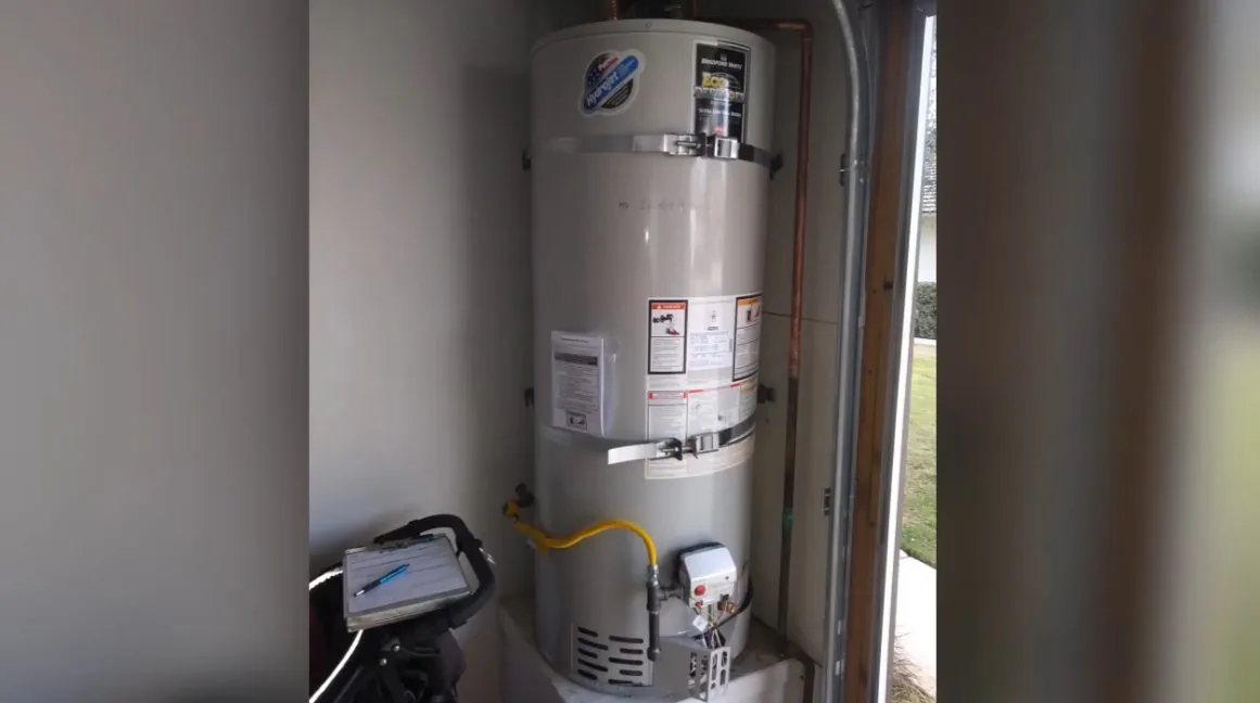 Gas tank water heater standing in a utility closet with a vent pipe overhead